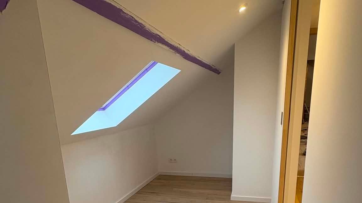 Combles aménagés : rampant sous poutre apparente, fenêtre de toit et parquet posé